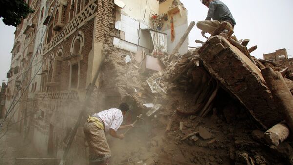 A man searches for survivors under the rubble of houses destroyed by Saudi airstrikes in the old city of Sanaa, Yemen, Friday, June 12, 2015 - Sputnik International