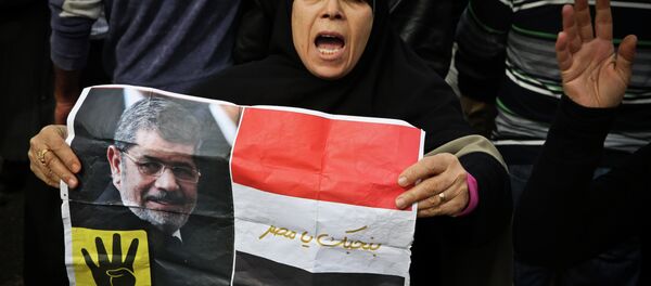 A supporter of the Muslim Brotherhood movement holds a placard showing ousted president Mohamed Morsi during a demonstration on January 24, 2015 in the Cairo district of Heliopolis A supporter of the Muslim Brotherhood movement holds a placard showing ousted president Mohamed Morsi during a demonstration on January 24, 2015 in the Cairo district of Heliopolis - Sputnik International