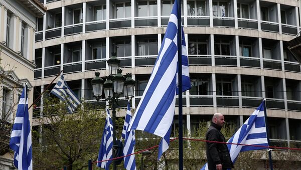 A municipal worker walks between Greek flags, which are placed on a stage for the celebrations of Orthodox Good Friday at central Metropoleos square in Athens, on Thursday, April 9, 2015 - Sputnik International