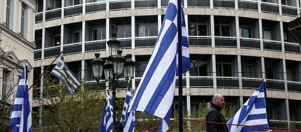 A municipal worker walks between Greek flags, which are placed on a stage for the celebrations of Orthodox Good Friday at central Metropoleos square in Athens, on Thursday, April 9, 2015 - Sputnik International