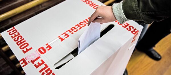 A voter casts a ballot in the voting box wrapped by tapes bearing letters that read: Sealed at a primary school in Copenhagen, Denmark, Thursday morning June 18, 2015 A voter casts a ballot in the voting box wrapped by tapes bearing letters that read: Sealed at a primary school in Copenhagen, Denmark, Thursday morning June 18, 2015 - Sputnik International