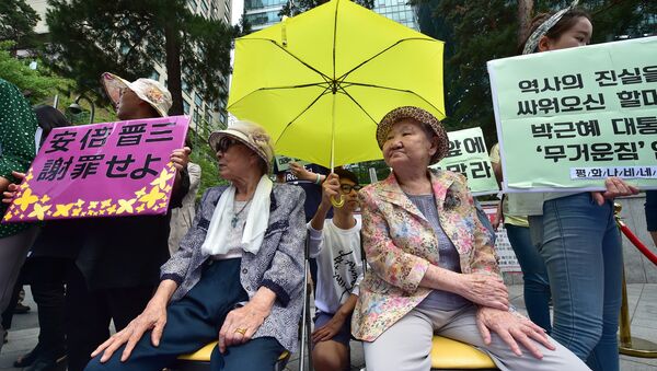 South Korean former comfort women Kim Bok-Dong (L) and Gil Won-Ok (R), who were forced to serve as sex slaves for Japanese troops during World War II, sit under a yellow umbrella during a press conference outside the Japanese embassy in Seoul on June 23, 2015 - Sputnik International