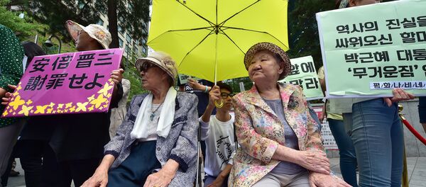 South Korean former comfort women Kim Bok-Dong (L) and Gil Won-Ok (R), who were forced to serve as sex slaves for Japanese troops during World War II, sit under a yellow umbrella during a press conference outside the Japanese embassy in Seoul on June 23, 2015 - Sputnik International