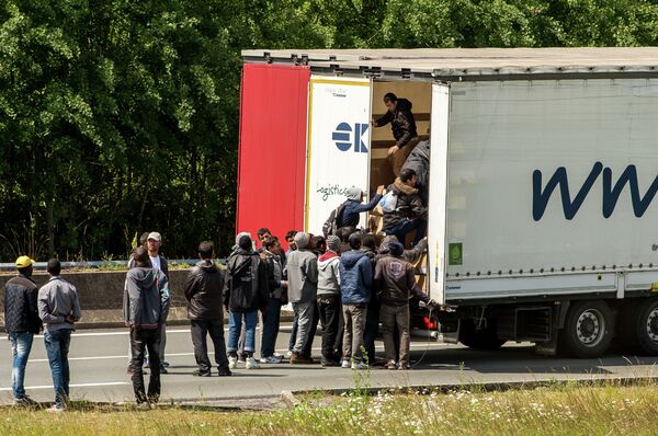 Migrants climb in the back of a lorry on the A16 highway leading to the Eurotunnel on June 23, 2015 in Calais, northern France Migrants climb in the back of a lorry on the A16 highway leading to the Eurotunnel on June 23, 2015 in Calais, northern France - Sputnik International