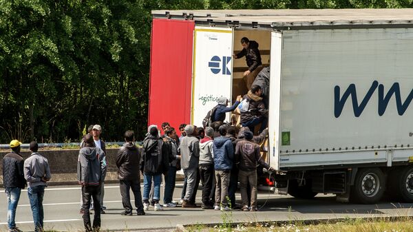 Migrants climb in the back of a lorry on the A16 highway leading to the Eurotunnel on June 23, 2015 in Calais, northern France - Sputnik International