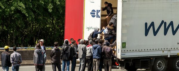 Migrants climb in the back of a lorry on the A16 highway leading to the Eurotunnel on June 23, 2015 in Calais, northern France - Sputnik International