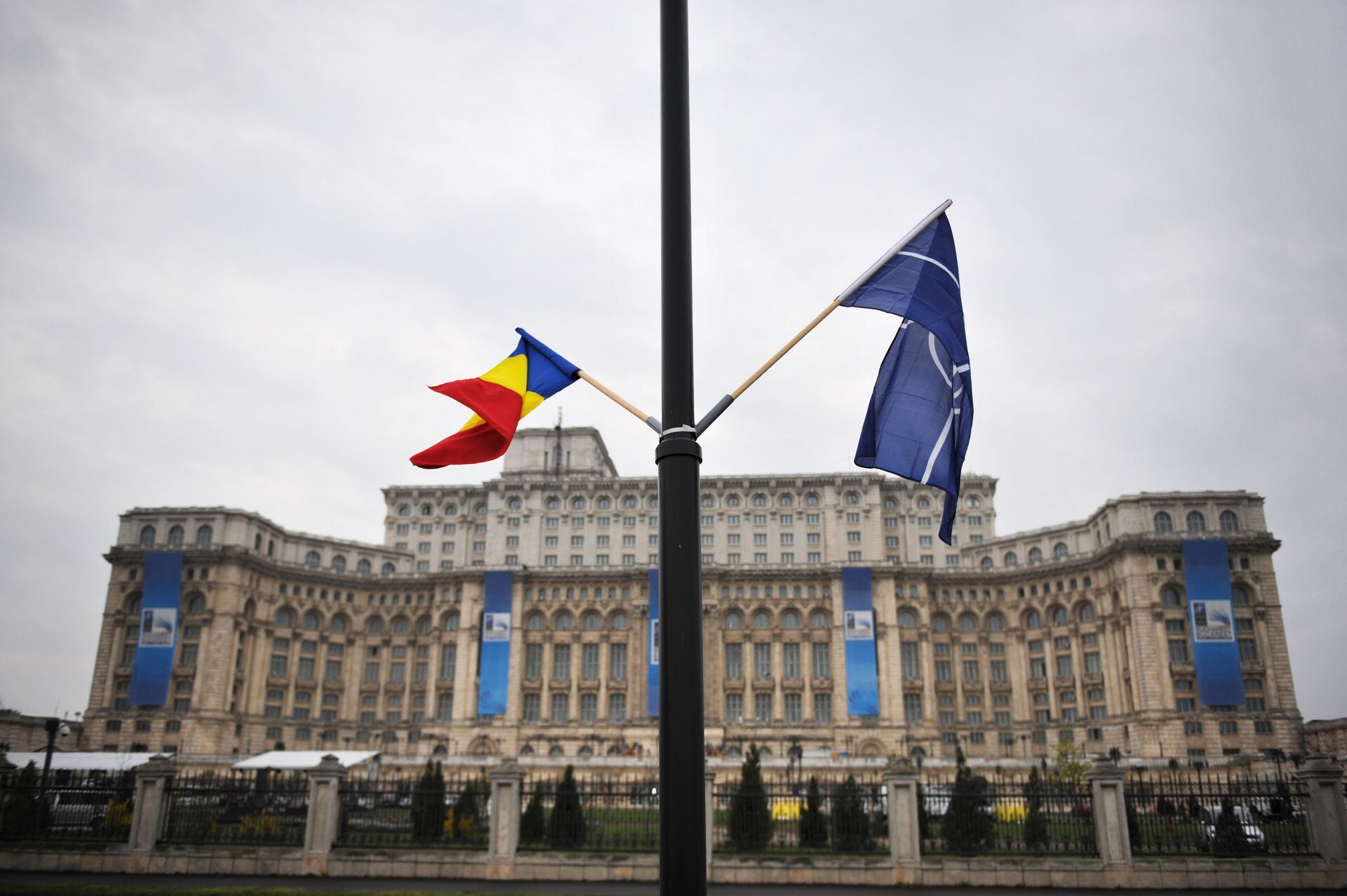 File photo of the Romanian and the NATO flag flutter in the wind in front of the Parliament Palace, the second largest building in the world after the Pentagon, in Bucharest on April 1, 2008 on the eve of the start of the NATO summit taking place form April 2 to 4 - Sputnik International, 1920, 21.08.2022