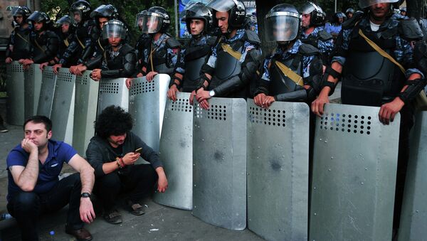 Demonstrators sit on a street in front of a line of riot police during a protest against an increase of electricity prices in the Armenian capital Yerevan on June 24, 2015 - Sputnik International