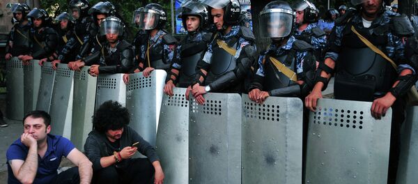 Demonstrators sit on a street in front of a line of riot police during a protest against an increase of electricity prices in the Armenian capital Yerevan on June 24, 2015 - Sputnik International