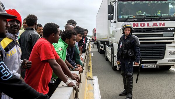 A French riot police officer (CRS) stands holdings his baton as illegal migrants wait to hide in lorries heading for England, in the French northern harbour of Calais, on June 17, 2015 - Sputnik International