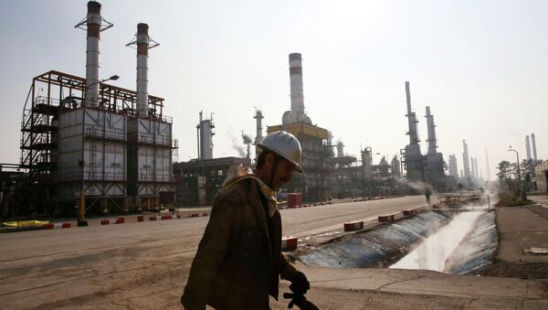 An Iranian oil worker makes his way through Tehran's oil refinery south of the capital Tehran, Iran, Monday, Dec. 22, 2014 - Sputnik International