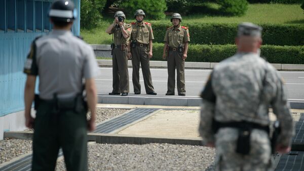 North Korean soldiers (C) take photos towards a South Korean soldier (L) and a US soldier (R) standing before the military demarcation line (lower C) seperating North and South Korea within the Joint Security Area (JSA) at Panmunjom on July 27, 2014 - Sputnik International