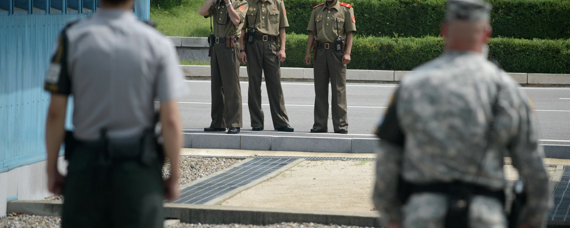 North Korean soldiers (C) take photos towards a South Korean soldier (L) and a US soldier (R) standing before the military demarcation line (lower C) seperating North and South Korea within the Joint Security Area (JSA) at Panmunjom on July 27, 2014 - Sputnik International, 1920, 19.07.2023
