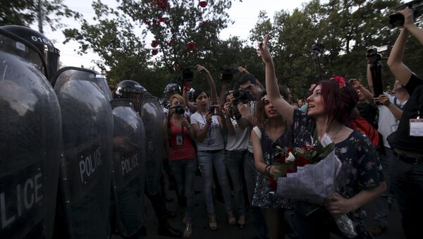 A protester throws rose petals in front of a line of riot police during a rally against a recent decision to raise public electricity prices in Yerevan, Armenia, June 23, 2015 - Sputnik International