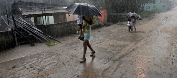 A woman carries her children in the rain as she walks by homes destroyed by flooding in Alajuela, Costa Rica A woman carries her children in the rain as she walks by homes destroyed by flooding in Alajuela, Costa Rica - Sputnik International