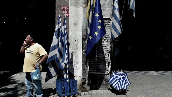 A man stands next to EU (European Union) and Greek flags in central Athens - Sputnik International