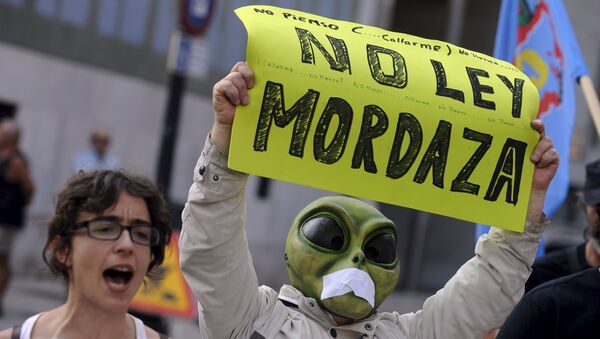 A man wearing a mask with a tape over the mouth holds up a sign during a protest against the Spanish government's new security law in Gijon, northern Spain, June 30, 2015 - Sputnik International