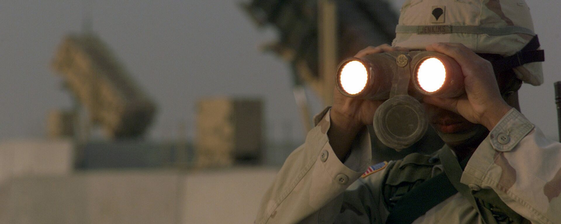 US soldier uses a pair of binoculars to scans the landscape around his Patriot Missiles based at Al Udeid AB, Qatar - Sputnik International, 1920, 10.09.2025