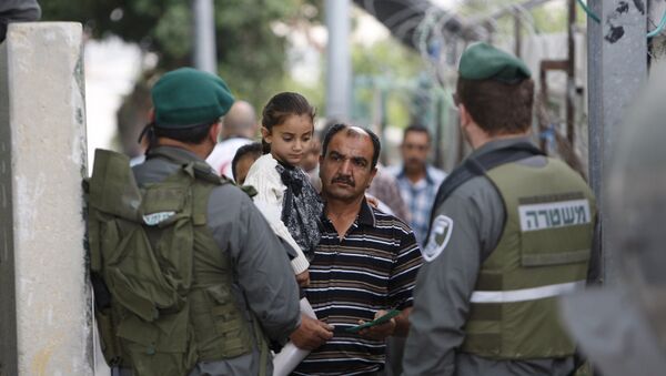 A Palestinian man carrying his daughter shows his identity card to Israeli border policemen at an Israeli checkpoint in the West bank city of Bethlehem June 26, 2015 - Sputnik International