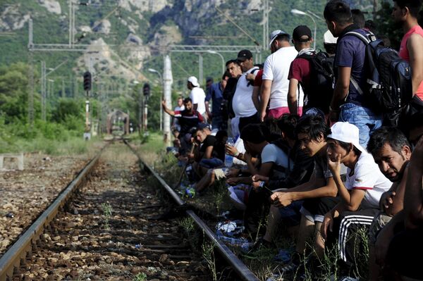 Migrants wait beside railway tracks for trains at Demir Kapia train station in Macedonia, near the border with Greece - Sputnik International