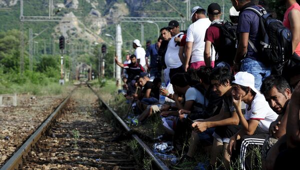 Migrants wait beside railway tracks for trains at Demir Kapia train station in Macedonia, near the border with Greece - Sputnik International