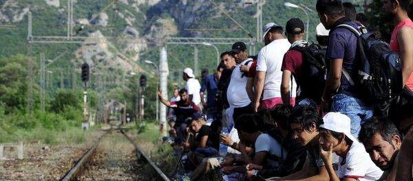 Migrants wait beside railway tracks for trains at Demir Kapia train station in Macedonia, near the border with Greece - Sputnik International