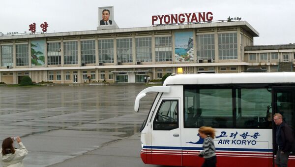This photo taken on September 21, 2010 shows a foreign visitor (L) taking pictures of Pyongyang airport with a portrait of late North Korean leader Kim Il-Sung on the roof in Pyongyang - Sputnik International
