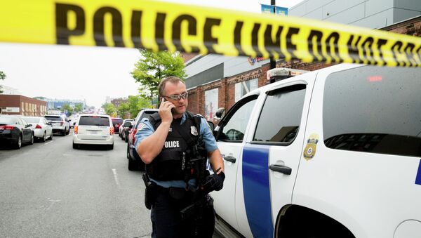 A police officer speaks on his phone as a large police presence gathers along M St. in Southeast Washington, Thursday, July 2, 2015, after an official said shots have been reported in a building on the Washington Navy Yard campus - Sputnik International