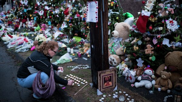 A woman lights candles at a makeshift memorial near the entrance to the grounds of Sandy Hook Elementary School on December 18, 2012 in Newtown, Connecticut - Sputnik International