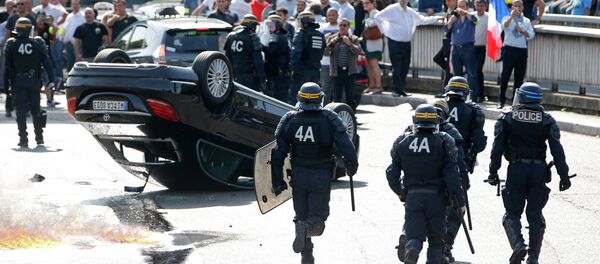 French riot police stand next to an overturned car as striking French taxi drivers demonstrate at the Porte Maillot to block the traffic on the Paris ring road during a national protest against car-sharing service Uber, in Paris, France, June 25, 2015 French riot police stand next to an overturned car as striking French taxi drivers demonstrate at the Porte Maillot to block the traffic on the Paris ring road during a national protest against car-sharing service Uber, in Paris, France, June 25, 2015 - Sputnik International