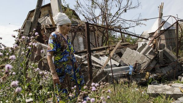A woman walks past her damaged house, which according to locals was hit by shelling on Wednesday, the village of Sakhanka in Donetsk region, Ukraine, July 2, 2015 - Sputnik International