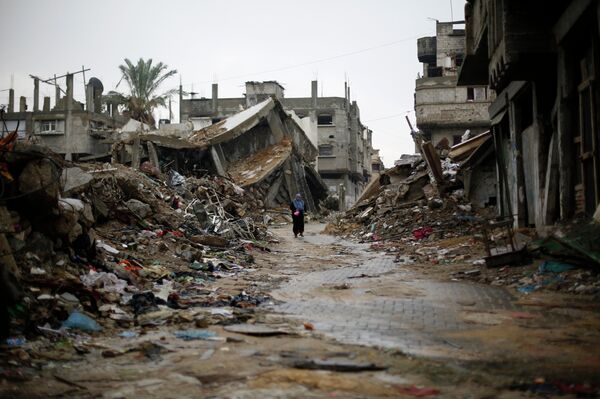 A Palestinian woman walks in the rain past houses that were destroyed during the 50-day Gaza war between Israel and Hamas-led militants, on November 24, 2014, in Gaza City A Palestinian woman walks in the rain past houses that were destroyed during the 50-day Gaza war between Israel and Hamas-led militants, on November 24, 2014, in Gaza City - Sputnik International