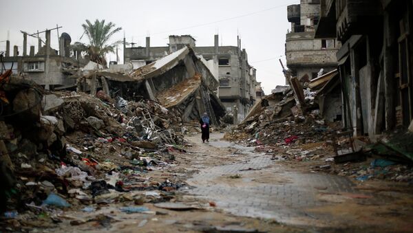 A Palestinian woman walks in the rain past houses that were destroyed during the 50-day Gaza war between Israel and Hamas-led militants, on November 24, 2014, in Gaza City - Sputnik International