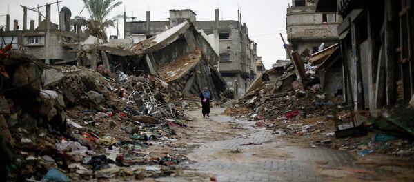 A Palestinian woman walks in the rain past houses that were destroyed during the 50-day Gaza war between Israel and Hamas-led militants, on November 24, 2014, in Gaza City A Palestinian woman walks in the rain past houses that were destroyed during the 50-day Gaza war between Israel and Hamas-led militants, on November 24, 2014, in Gaza City - Sputnik International