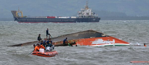 Rescuers tie a rope at the capsized vessel MBCA Kim-Nirvana to pull it towards the shore near a port in Ormoc city, central Philippines, July 3, 2015 Rescuers tie a rope at the capsized vessel MBCA Kim-Nirvana to pull it towards the shore near a port in Ormoc city, central Philippines, July 3, 2015 - Sputnik International