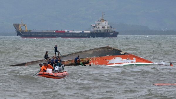 Rescuers tie a rope at the capsized vessel MBCA Kim-Nirvana to pull it towards the shore near a port in Ormoc city, central Philippines, July 3, 2015 - Sputnik International