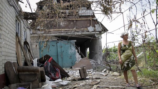 A woman walks in front of her damaged house, which according to locals was hit by shelling on Wednesday, the village of Sakhanka in Donetsk region, Ukraine, July 2, 2015 - Sputnik International