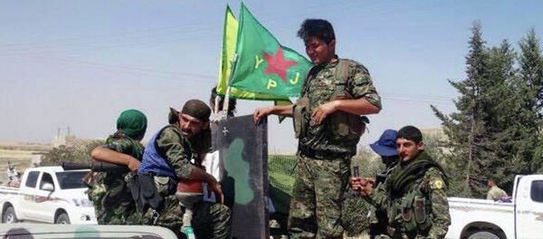 In this photo provided by the Kurdish fighters of the People's Protection Units (YPG), which has been authenticated based on its contents and other AP reporting, Kurdish fighters of the YPG, sit on their pickup in the town of Ein Eissa, north of Raqqa city, Syria, Tuesday, June 23, 2015 - Sputnik International