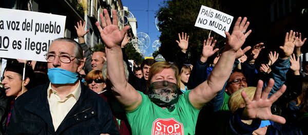 Demonstrators hold placards reading A country with a gag doesn't move as they protest against the new public security law (ley mordaza) approved by the lower house of parliament, in Madrid on December 20, 2014 - Sputnik International