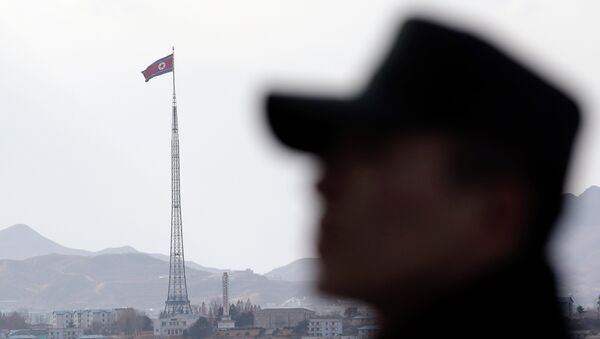 A South Korean soldier stands as a North Korean flag flutters in the wind atop a 160-meter (533-foot) tower in the village of Gijungdong near the north side of the border village of Panmunjom, which has separated the two Koreas since the Korean War, in Paju, north of Seoul, South Korea, Wednesday, Nov. 12, 2014 - Sputnik International