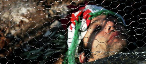 An Israeli activist lays behind wire fencing as he and others try to stop Israeli bulldozers, not seen, from working, during a joint protest with Israelis, Palestinians and foreign peace activists against Israel's seperation barrier in the West Bank. - Sputnik International