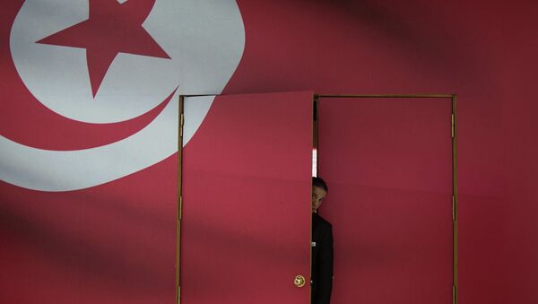 A Tunisian guard looks out of the main gate of media center for its parliamentary election in Tunis, capital of Tunisia, on Oct. 25, 2014 - Sputnik International