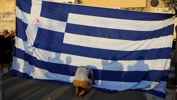 A protester kneels to pay his respect in front of a Greek flag during an anti-austerity rally in Athens, Greece, June 29, 2015 - Sputnik International