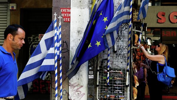 A woman looks at sandals from a shop as an a man passes by Greek and European Union flags in central Athens, Wednesday, July 8, 2015 - Sputnik International