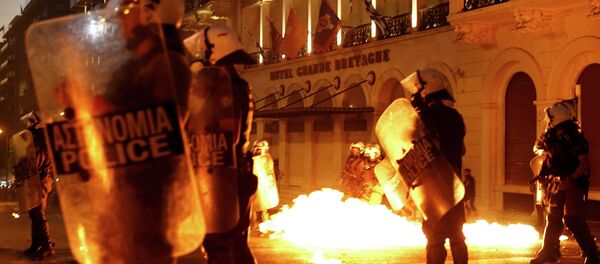 Riot police stand amongst the flames from exploded petrol bombs thrown by a small group of anti-austerity demonstrators in front of parliament in Athens, Greece July 15, 2015 - Sputnik International
