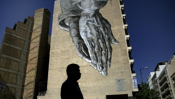 A pedestrian walks through empty streets by a mural in Athens, Greece - Sputnik International