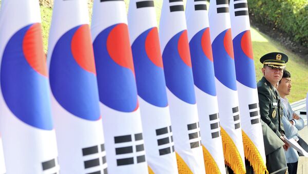 A South Korean military officer (R) stands next to a line of national flags during a ceremony to mark the 64th Korea Armed Forces Day at the military headquarters in Gyeryong, about 140 km south of Seoul, on September 25, 2012 - Sputnik International