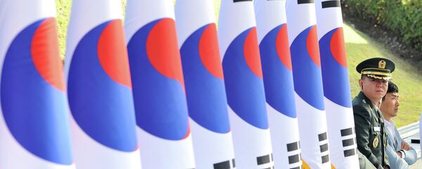 A South Korean military officer (R) stands next to a line of national flags during a ceremony to mark the 64th Korea Armed Forces Day at the military headquarters in Gyeryong, about 140 km south of Seoul, on September 25, 2012 - Sputnik International