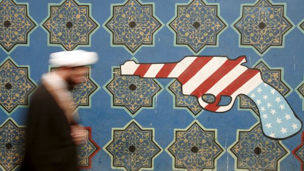An Iranian cleric walks past a mural on the wall of the former U.S. embassy in Tehran in this February file photo. - Sputnik International