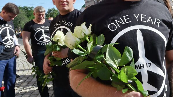 People wearing t-shirts bearing a drawing of a plane and slogans reading  MH 17, One year in the skies hold flowers to the Dutch embassy in Kiev on July 17, 2015 in memory of the people who died in the crash of Malaysian Airlines flight MH17 - Sputnik International